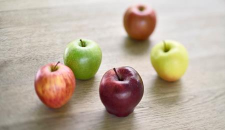 Diverse mele dell’Alto Adige di colori differenti appoggiate su un tavolo in legno.