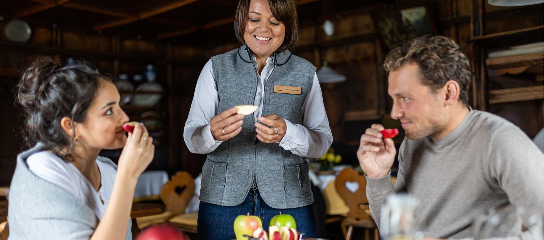 Due persone degustano mele, una donna le consiglia durante la degustazione