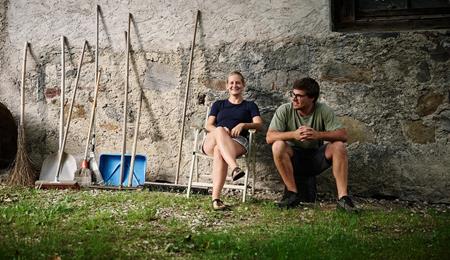 Andrea Erlacher e Jacob Gamper siedono insieme davanti al maso, accanto a diversi attrezzi da lavoro.